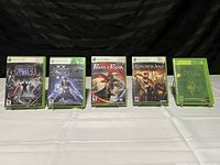 Five Xbox 360 game cases arranged in a row on a white cloth surface, showing front covers with characters and titles.