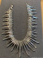 Full view of the silver-tone metal statement necklace with spiky elements laid flat to show entire design and box clasp.