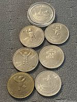 Seven different Carnaval de Quebec and maritime commemorative coins arranged on a textured dark surface. Coins feature Bonhomme Carnaval mascot and various logos with dated inscriptions.