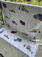 Full view of the handmade quilt draped showing construction vehicle appliqués and overall design.