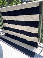 Full view of flatweave rug hanging showing horizontal black and ivory stripes.
