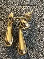 Pair of polished yellow gold teardrop dangle earrings shown from side angle revealing stud post and butterfly backs