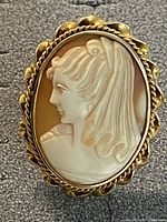 Close-up of cameo brooch showing detailed profile carving and gold frame