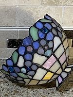 Side view of the stained glass lamp shade showing the multicolored pastel floral mosaic pattern and scalloped edge.