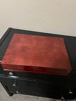 Closed wooden box with reddish finish, showing wear.