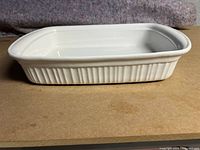 Side profile of white rectangular stoneware baking dish with ribbed/fluted exterior sides.