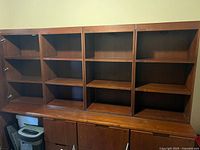 Front view of the seven piece Kimball office credenza showing open shelving over file drawers with wood finish.