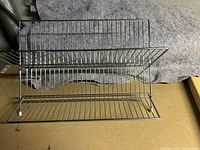 Image of a chrome folding dish rack with grid structure for dish placement.