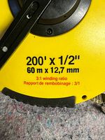 Close up photo of yellow plastic casing showing 200' x 1/2'' and 60m x 12.7mm details with 3:1 winding ratio indication.
