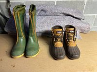 Pair of green Kamik high top insulated waterproof boots with orange drawstring closure and brown Oshkosh duck boots with lace-up closure