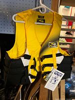 Front view of the yellow Fluid nylon PFD with logos and adjustable straps visible on hanger.