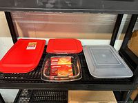 Shelf display of four baking pans including Pyrex and Bakers Secret, showing lids and pan sizes.