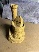 Front angle view of the sand castle sculpture showing tower, house, and circular wall details.