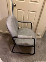 Side angle of one gray office guest chair showing fabric seat and backrest with padded armrests and black metal sled frame