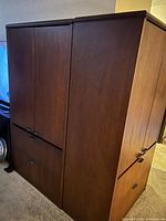 Exterior view of two tall wooden storage cabinets side by side, showing doors and drawer fronts.