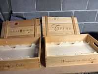 Two wooden 6-bottle wine boxes side by side, one labeled Peller Estates and the other Trius, with internal slots for bottles visible.