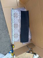 Photo showing rubber-backed side of rectangular stair tread and ruler for scale.