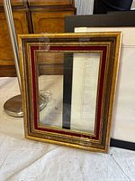 Gold frame with decorative border alongside black frames in background