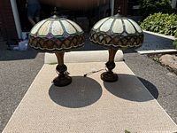 Two Tiffany style lamps displayed side by side on outdoor surface