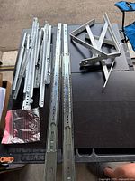 Includes multiple steel heavy duty drawer slides, metal corner hangers visibly stacked on table surface.