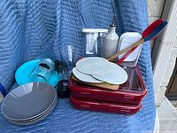Kitchen items including glass vase, blender, melamine plates, ceramic pasta dishes, containers, trivets, and utensils
