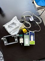 Top-down view of all items arranged on dark table showing two Leviton switches in boxes, metal outlet box, sealed white faceplate, yellow wire connector, wired cord, and cylindrical components.