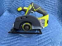 Side view of the Ryobi cordless handheld circular saw showing blade guard and handle.