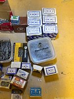 Photo showing multiple labeled boxes of nails including sizes 1 to 3 inches, plastic containers with loose nails, and boxes from Stelco and other brands.
