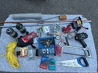 Entire lot spread out on blanket showing tools, pipes, charger, saws, lights, propane canisters, clamps, rope and hardware