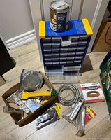 Photo of tool room lot showing wall mountable storage organizer, wood stain can, metal hose, hardware, and assorted tools