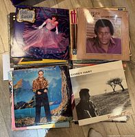 Stack of vinyl LP records featuring Linda Ronstadt, Charley Pride, Elton John, Corey Hart.