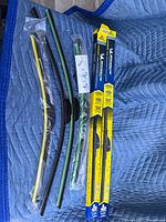 Photo showing three new windshield wiper blades, with 2 in yellow packaging and one loose, sizes 20" and 26".