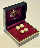 Two pairs of pearl stud earrings displayed in a Weber branded jewelry box with burgundy velvet interior.