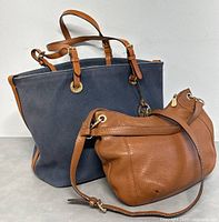 Two Michael Kors bags together showing size and color difference, the navy tote and brown shoulder bag.