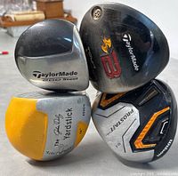 Top view of golf club heads showing TaylorMade 200 Steel, TaylorMade Tour Burner 3 B, The Jack Nicklaus Yardstick, and Wilson ProStaff driver heads.