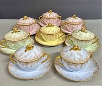 Eight lidded bouillon soup cup sets arranged front view showing pastel color variety