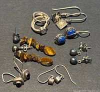 Overview of eight pairs of vintage 925 silver earrings with various designs including hoops, drops, studs, and semi-precious stones.