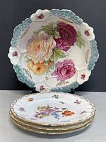 Photo showing one signed German porcelain shallow bowl with large floral design and three Dresden porcelain side plates stacked in front.