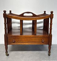 Frontal view of magazine rack showing curved handle, spindle supports, drawer and casters