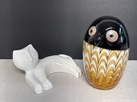 Both items side by side showing the art glass owl paperweight and porcelain cat figurine