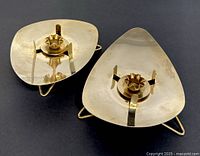 Top angled view showing two brass candle holders with triangular concave bases and prong candle holders in center, polished brass surface.