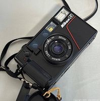 Front view of camera showing lens, viewfinder, flash and red accent line