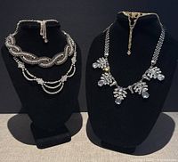 Two rhinestone choker necklaces displayed on black bust stands showing design and condition.