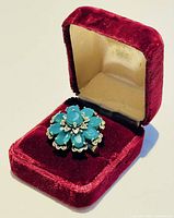 Vintage silver ring with green quartz gemstones displayed in a red velvet jewelry box.