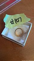 Ring in small white jewelry box with yellow tape labeled #107