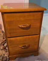 Front view of the nightstand showing two drawers with integrated wooden handles.
