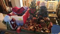 Overview of multiple Christmas decorations including Santa figure, miniature trees, and assorted ornaments in bins