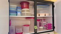 Various sizes of plastic food storage containers stacked on shelves, including blue, red, and pink lids.