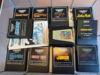 Top-down view of eleven ColecoVision game cartridges with original labels, some with manual papers beneath them.