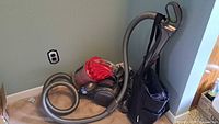Dyson DC32 canister vacuum with hose, wand and attachments on carpet by wall